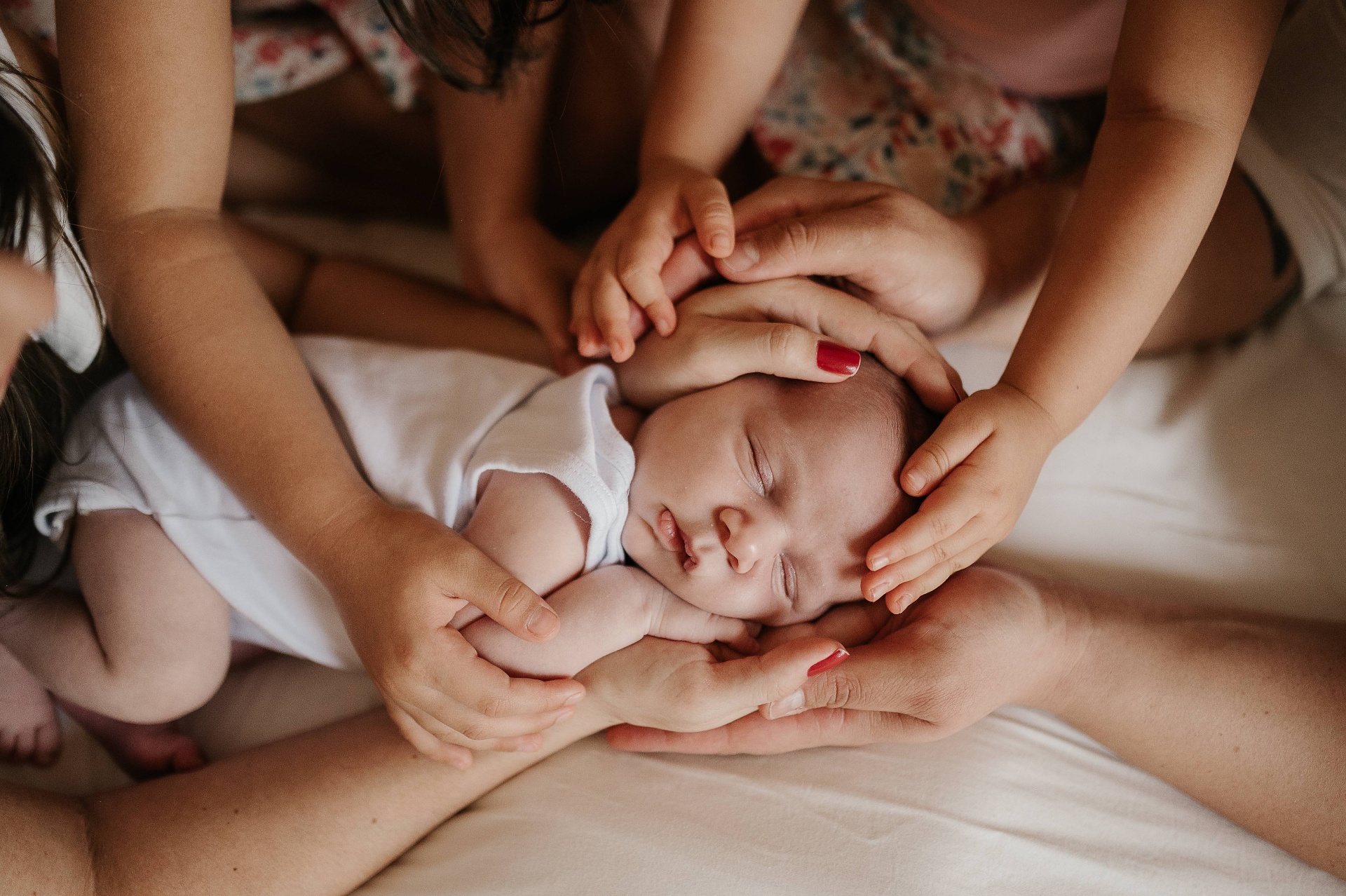 Mãos da família em concha ao redor do bebê recém-nascido